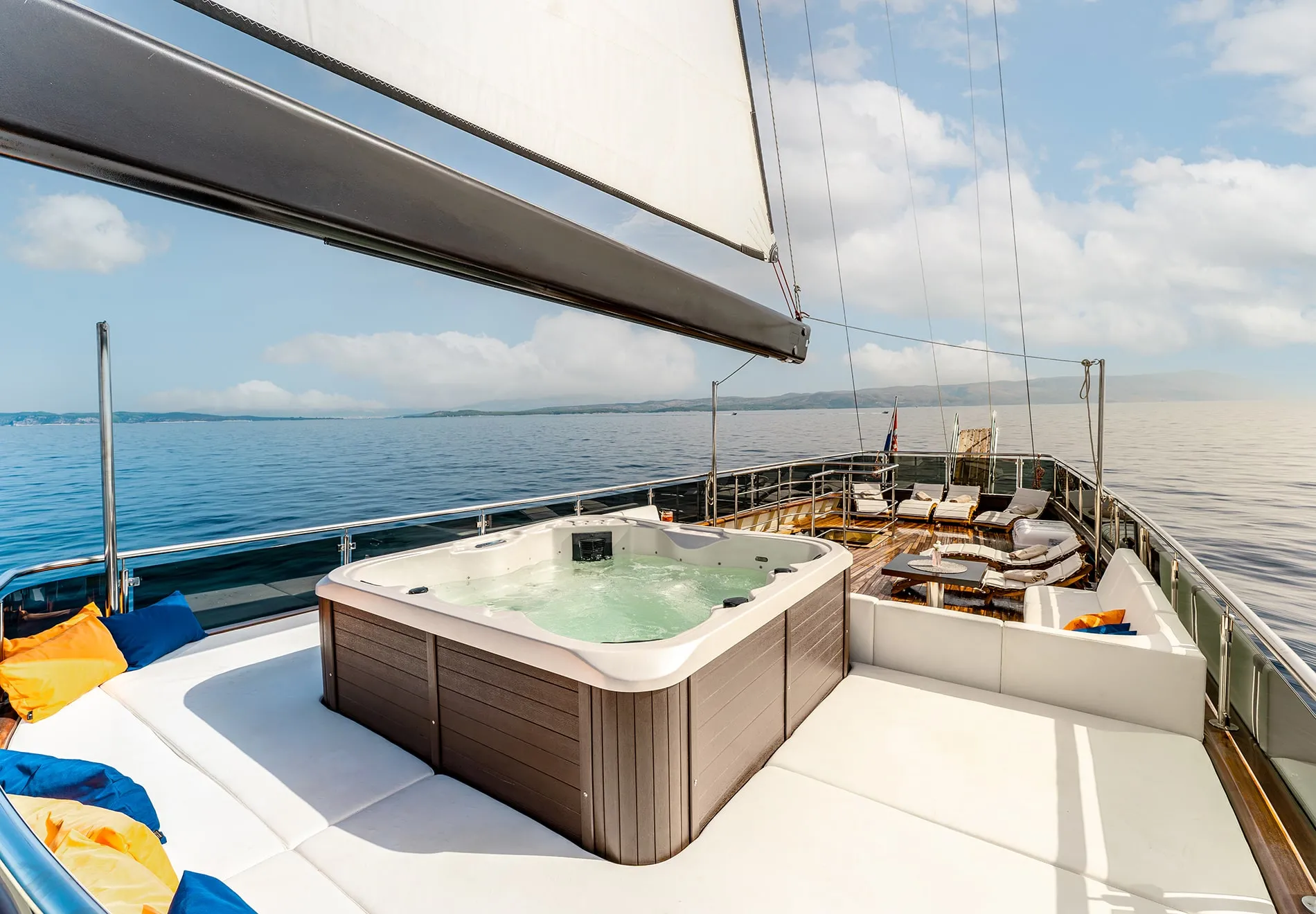 The sun deck, featuring teak floors, padded lounging areas, and a jacuzzi, is the yacht’s highlight. Guests can relax, dine under the stars, or