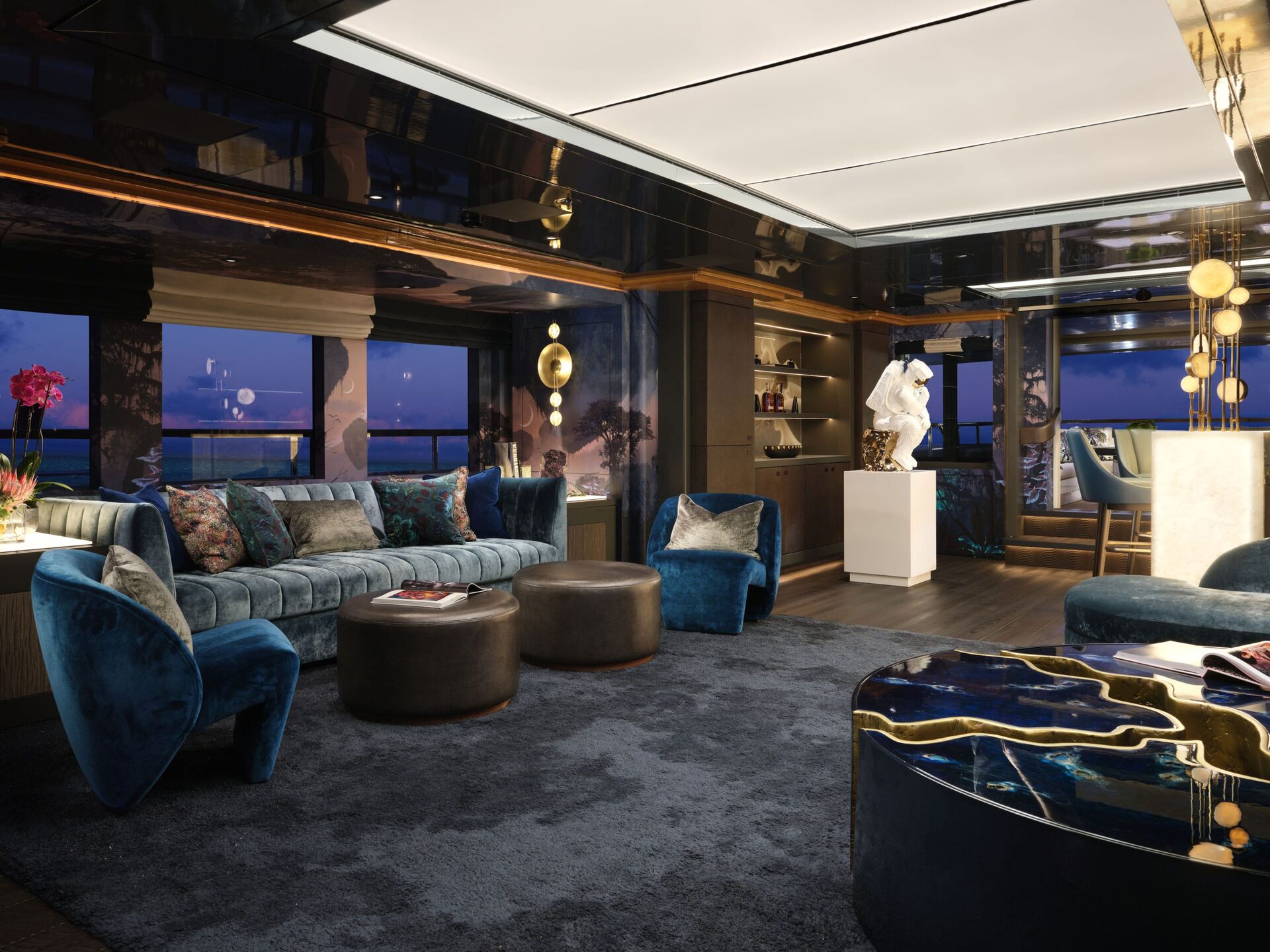 Modern luxury yacht lounge with velvet blue seating, round ottomans, a dark rug, contemporary decor, a white sculpture, large windows with ocean views, and stylish lighting creating a sophisticated atmosphere.