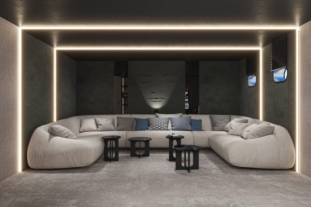 A modern lounge with a large, curved beige sofa, black side tables, and soft lighting outlining the ceiling and walls. A serene face artwork decorates the dark back wall, adding a calming atmosphere.