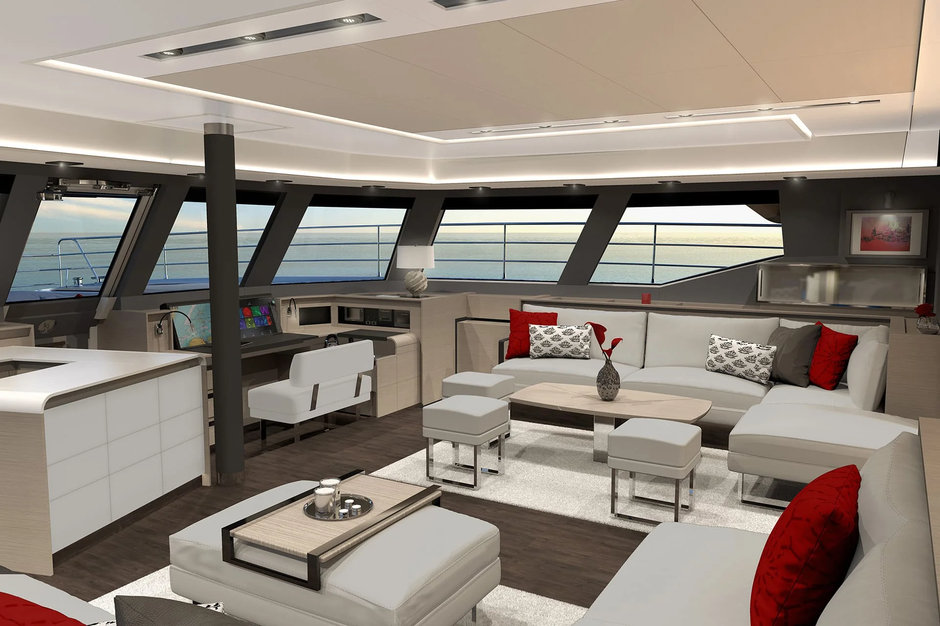 Modern yacht interior with large windows, white and gray furniture, red accent pillows, a small kitchen area, and an ocean view at sunset.