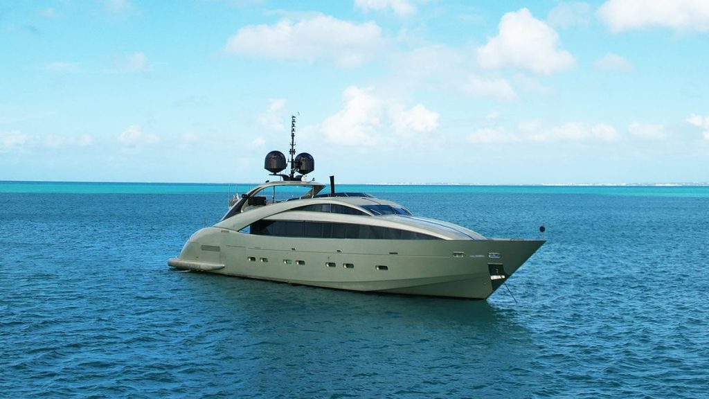 YCM 120 A sleek, modern yacht with a streamlined design floats on calm blue ocean water under a partly cloudy sky.