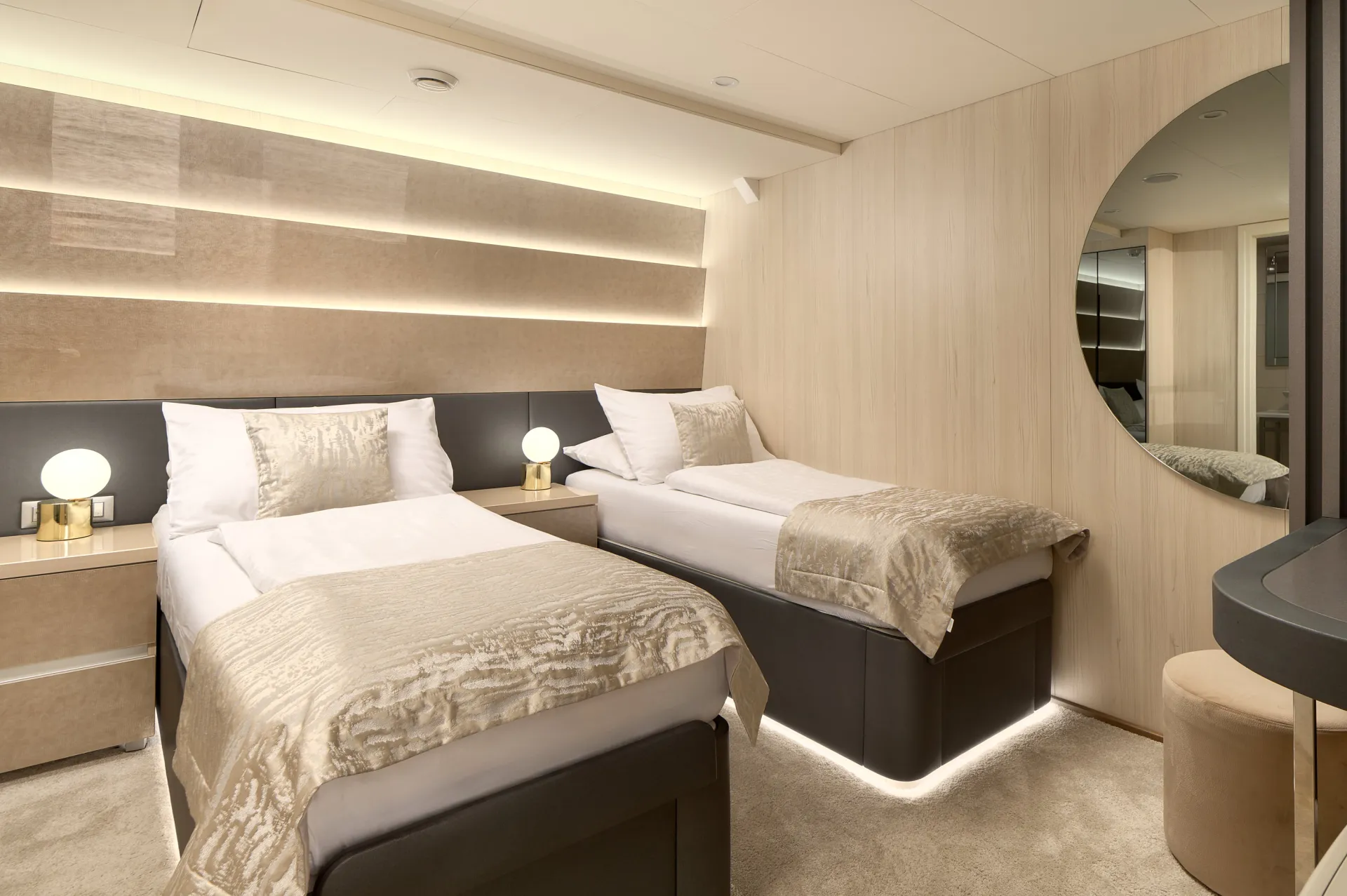 CRISTAL A modern, well-lit bedroom with two single beds, beige bedding, a round wall mirror, soft lighting, and minimalist decor featuring neutral tones and sleek furniture.