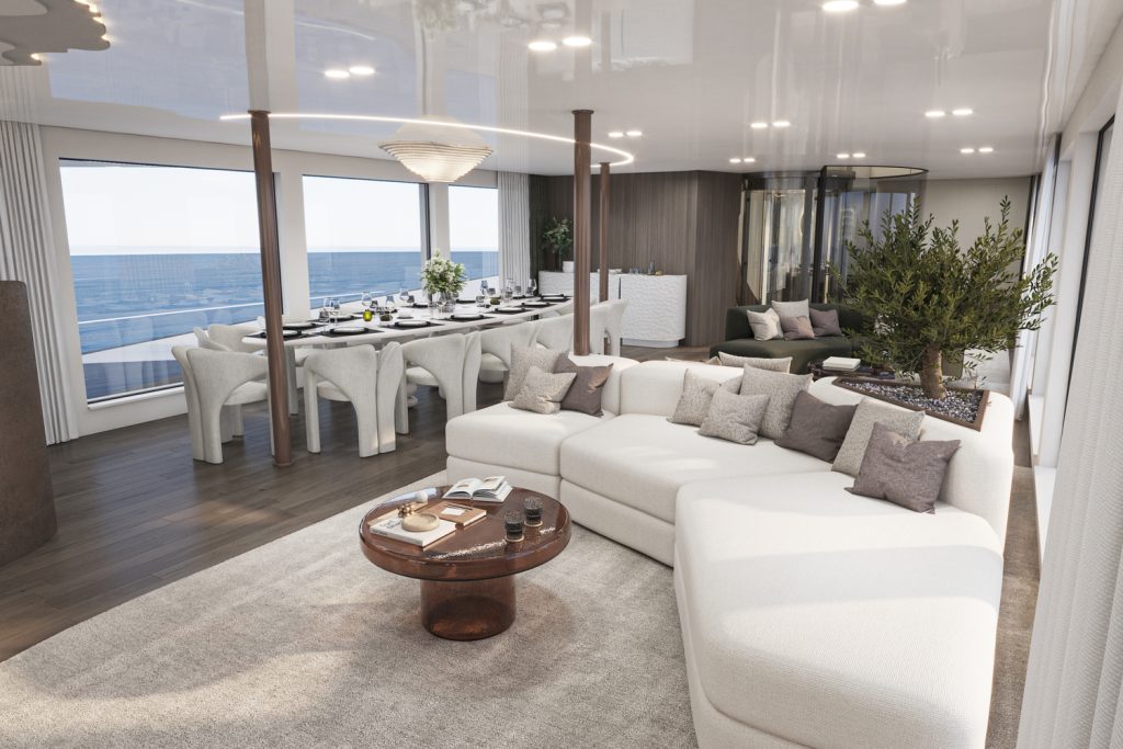 Modern open-plan living and dining area with large windows overlooking the ocean, featuring a white sectional sofa, round coffee table, dining table with white chairs, potted plant, and neutral, elegant decor.
