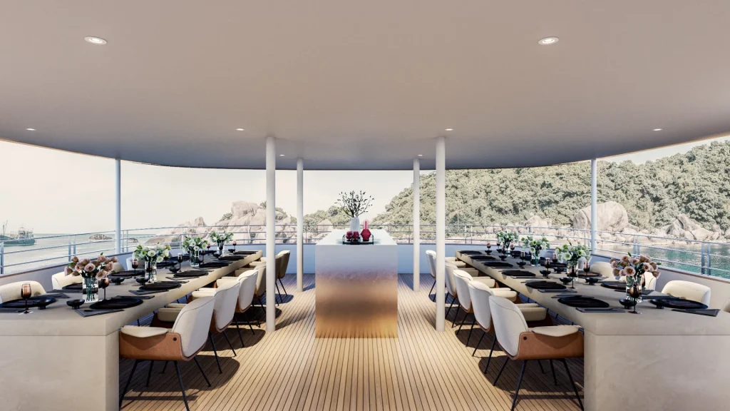 PREMIER A modern outdoor dining area on a yacht features two long tables with elegant place settings and cushioned chairs, overlooking the ocean and green hills through open sides.