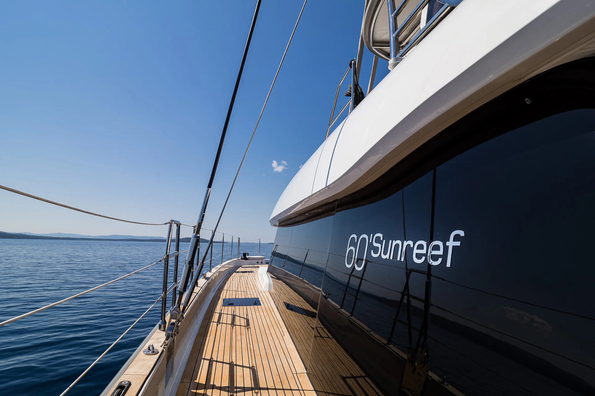 Side deck of a 60 Sunreef catamaran with a wooden deck and railings overlooking the ocean.