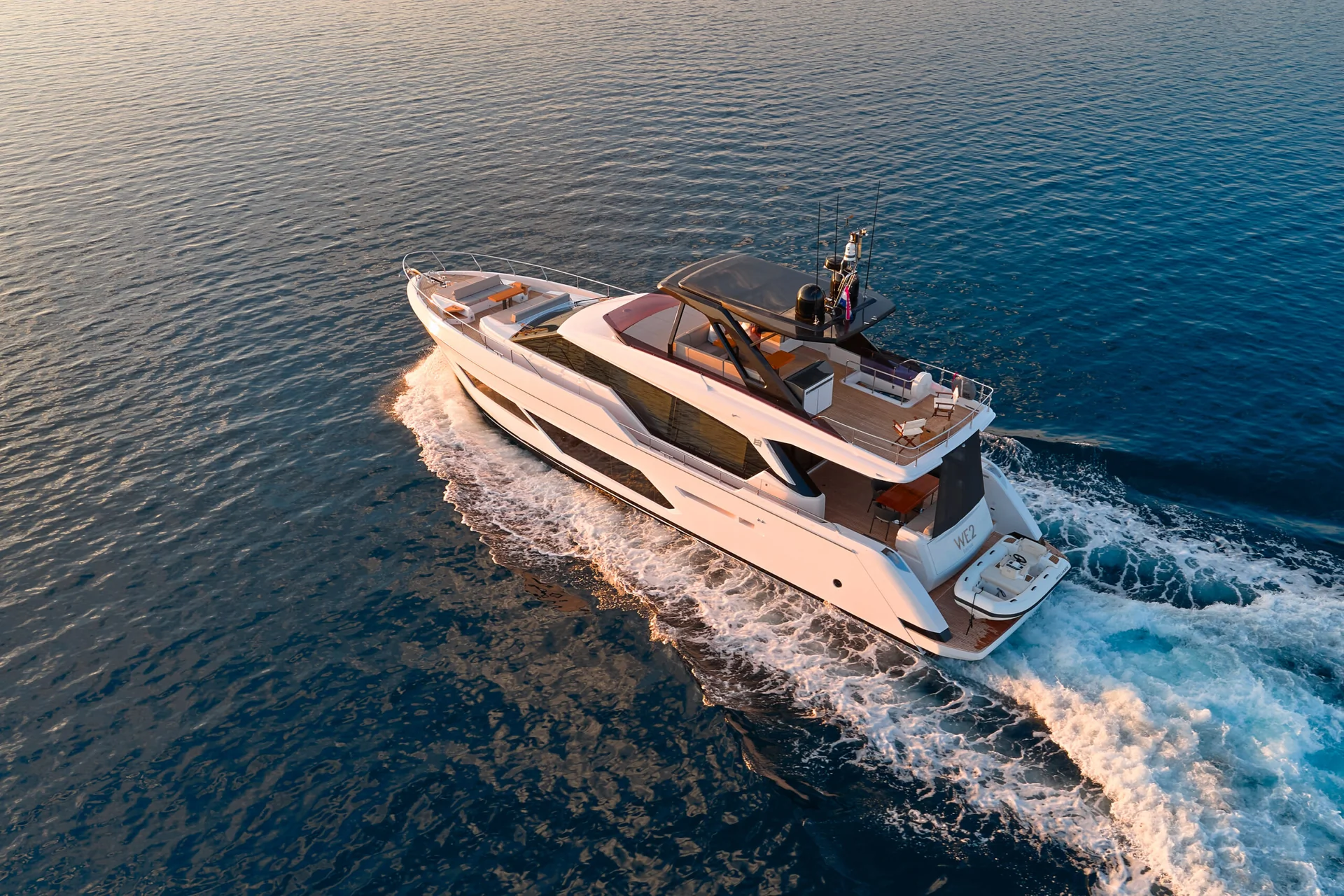 A white luxury yacht cruising through calm blue water, leaving a wake behind it.