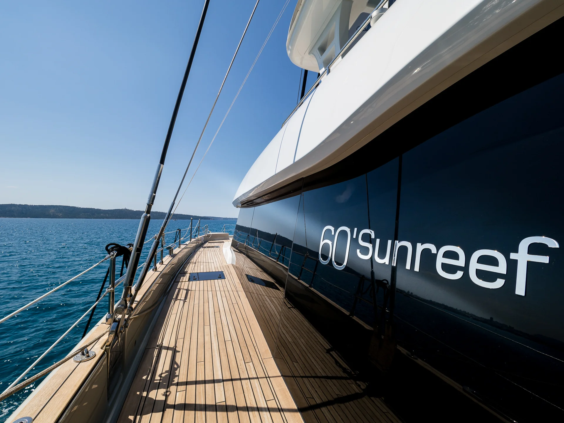 The wooden deck and side profile of a yacht with 60 Sunreef written on the dark glass window.