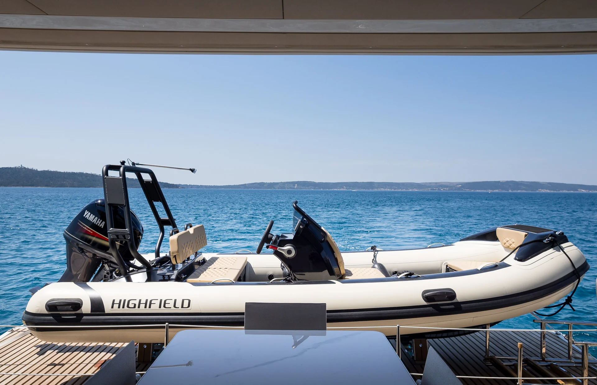 A white Highfield rigid inflatable boat with a black Yamaha outboard motor, moored behind a yacht.